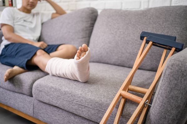 A person after breaking their leg, wondering what to do after being injured with crutches at the end of the sofa